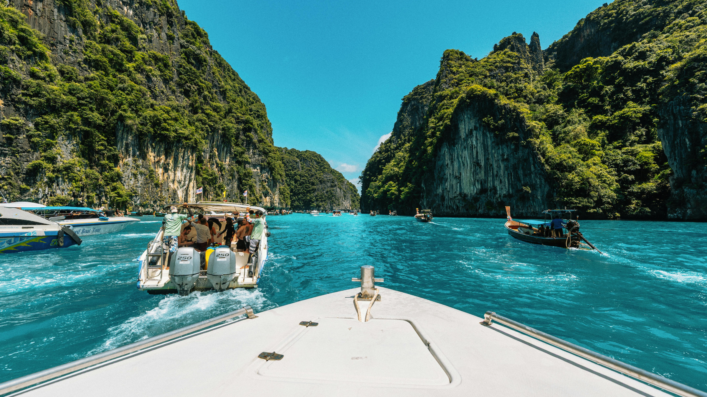 View from a boat approaching limestone cliffs and turquoise water in Thailand